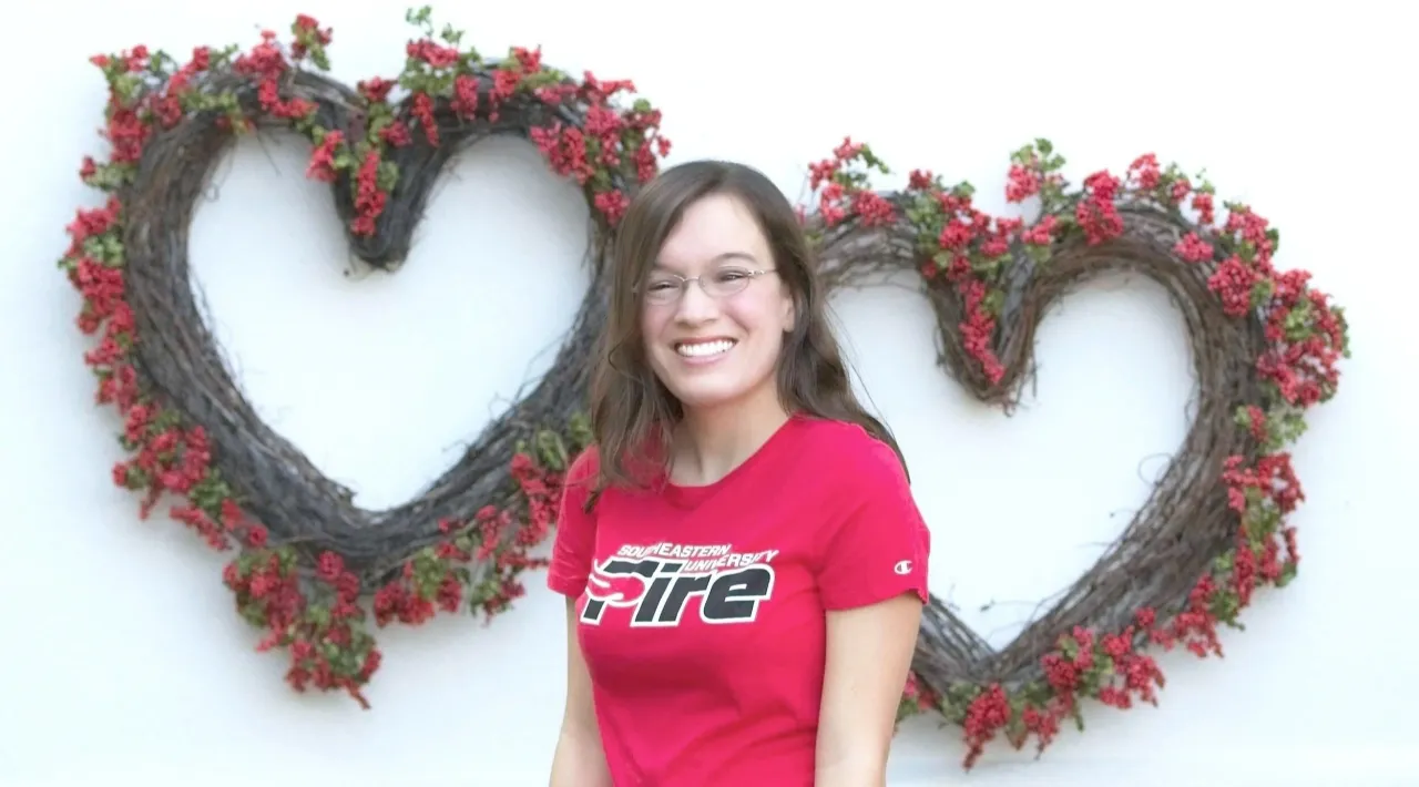Marisa D'Amore smiling in front of heart-shaped palm trees